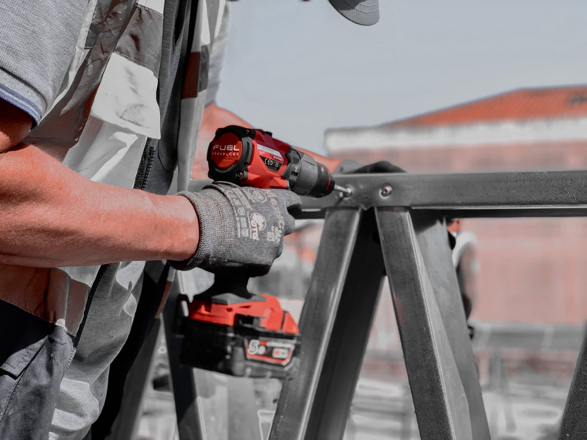 Trabalhador com parafusadora vermelha a montar perfil LSF