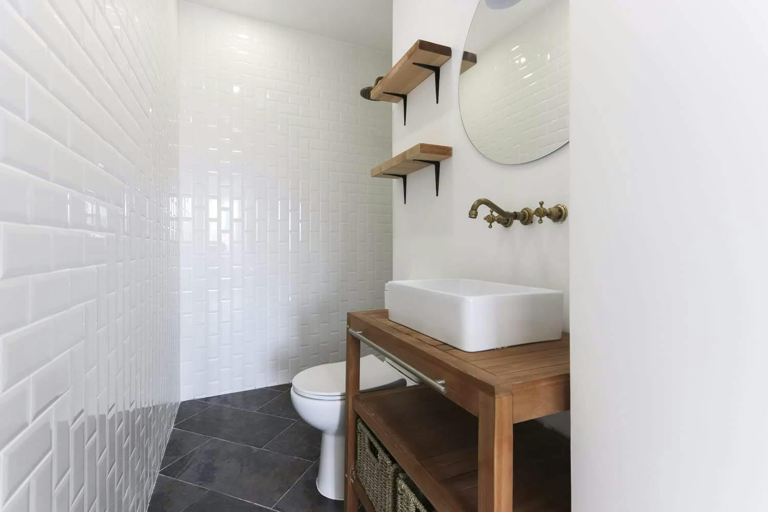Casa de banho com azulejo branco e móveis de madeira